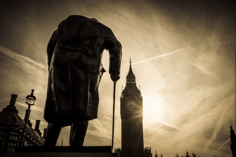 Churchill's statue in Parliament Square in silhouette, with Big Ben behind