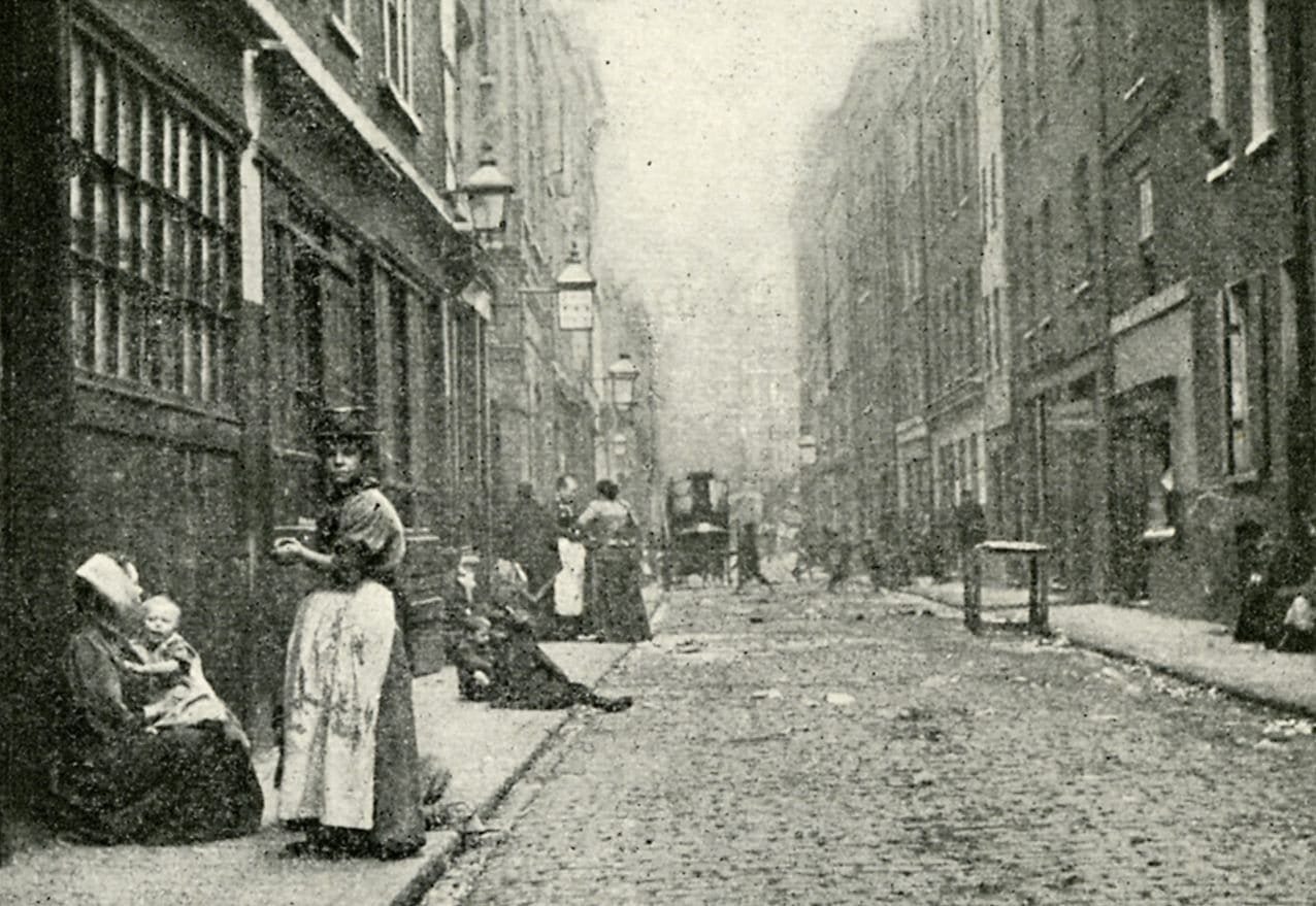Dorset Street in 1902, a narrow street of soot-blackened lodging houses with women and children on the pavement