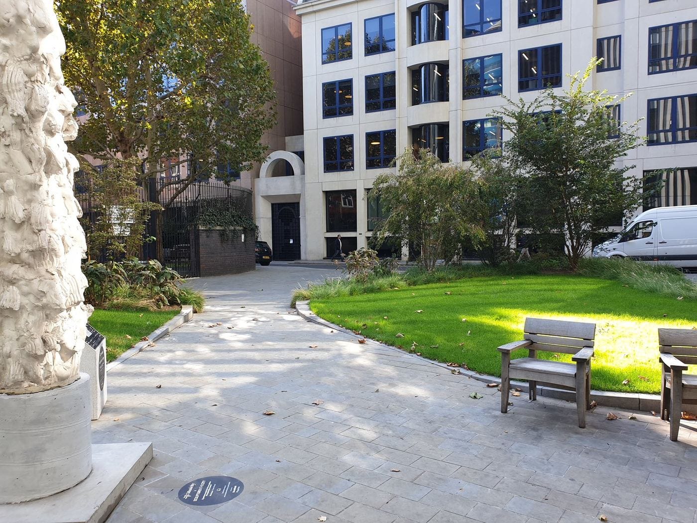 Mitre Square in the City of London today, with a lawn, benches and young trees in front of office buildings