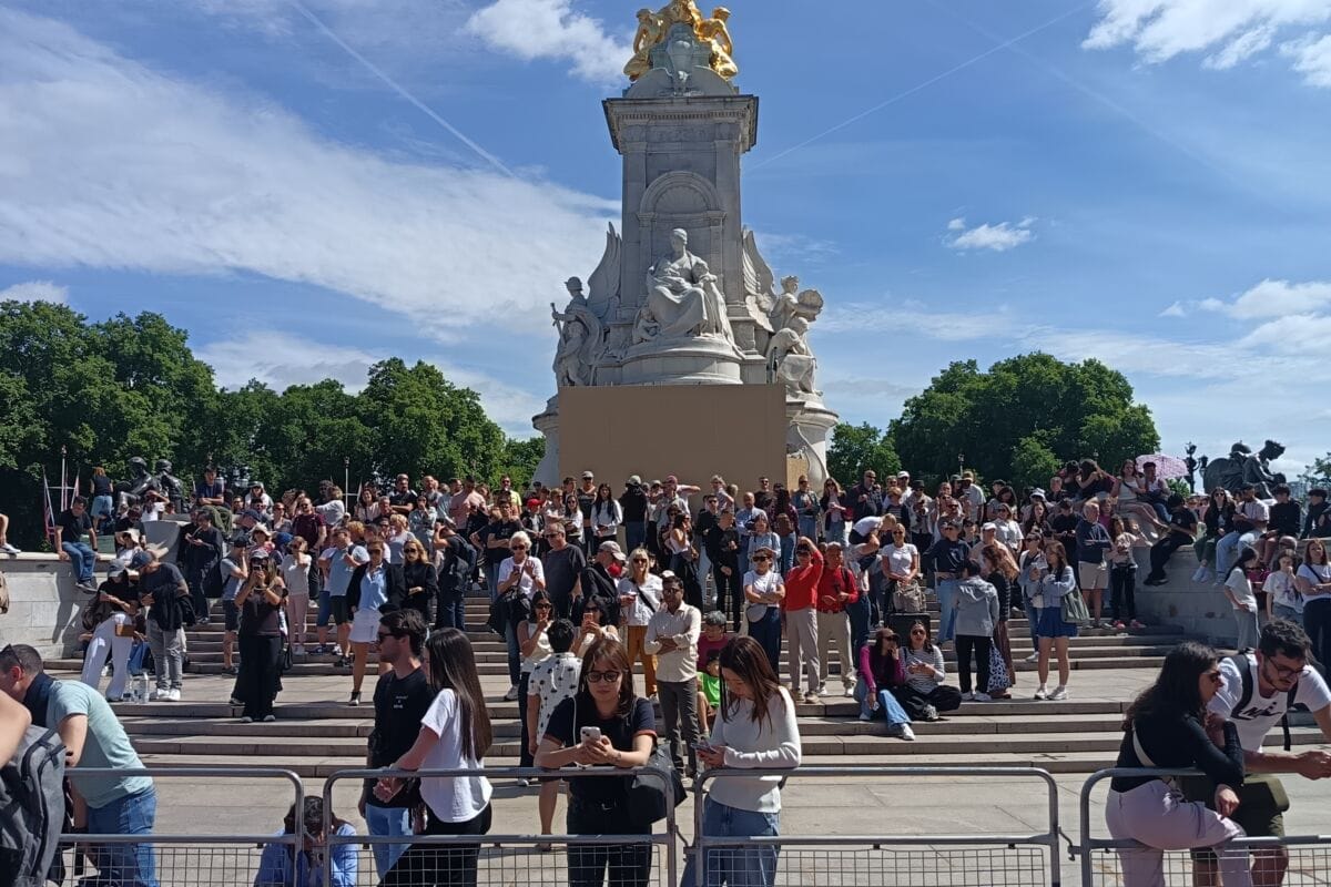 The Queen Victoria Memorial outside Buckingham Palace, with visitors waiting on the steps and behind the barriers before Changing the Guard